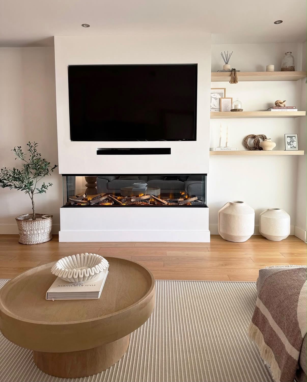 Ivory plastered media wall with inset fireplace, wall-mounted TV and floating oak shelving alcove