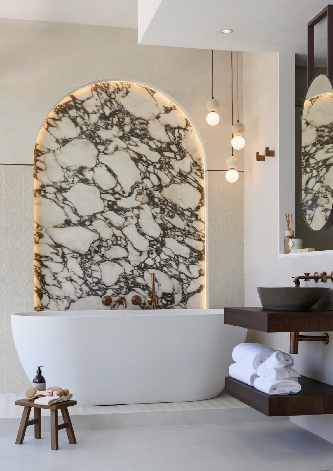 Spa bathroom with a backlit Calacatta Viola marble arch, freestanding tub and aged brass fittings
