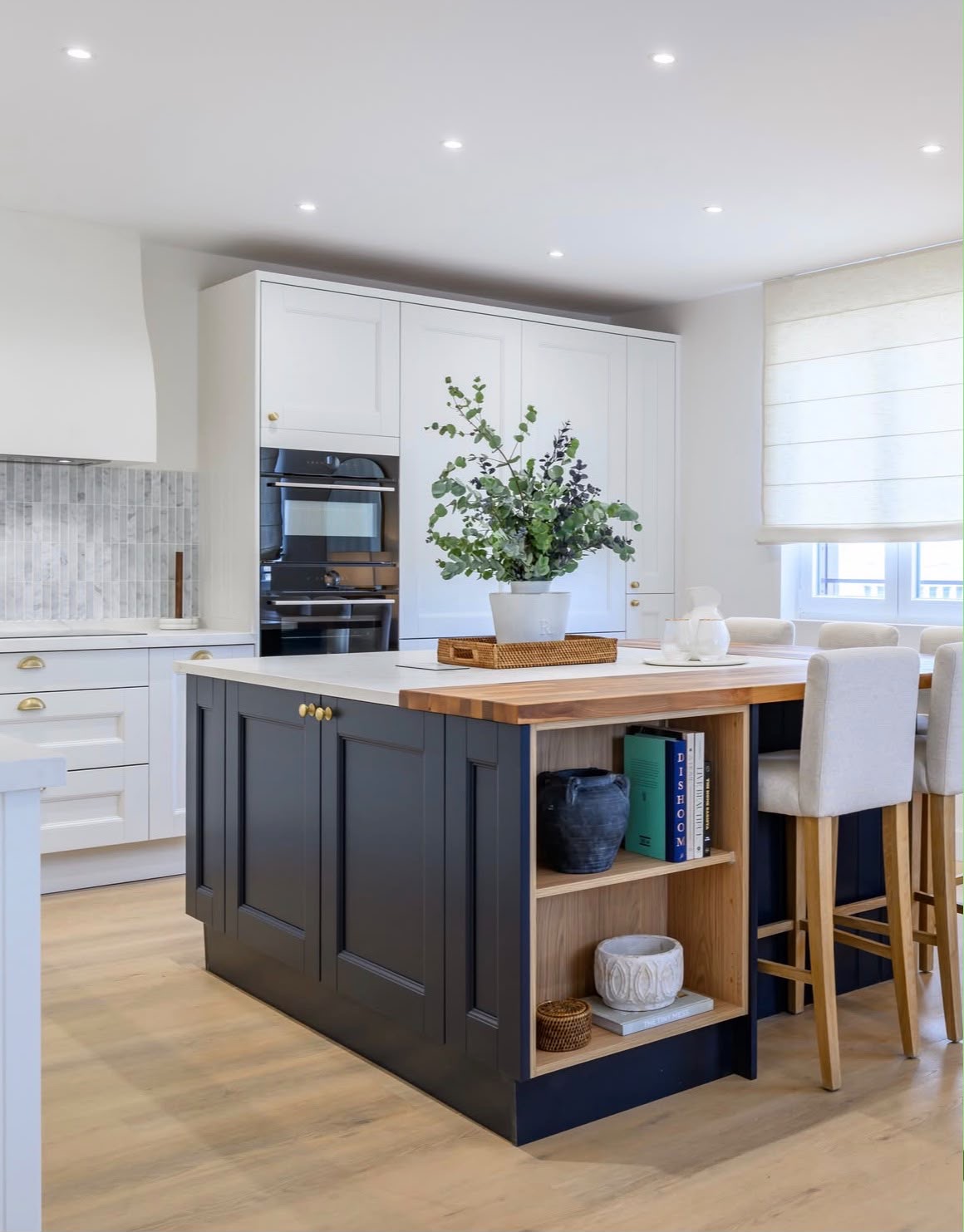 Classic shaker kitchen with a navy island, butcher block breakfast bar, brass cup handles and marble tiling
