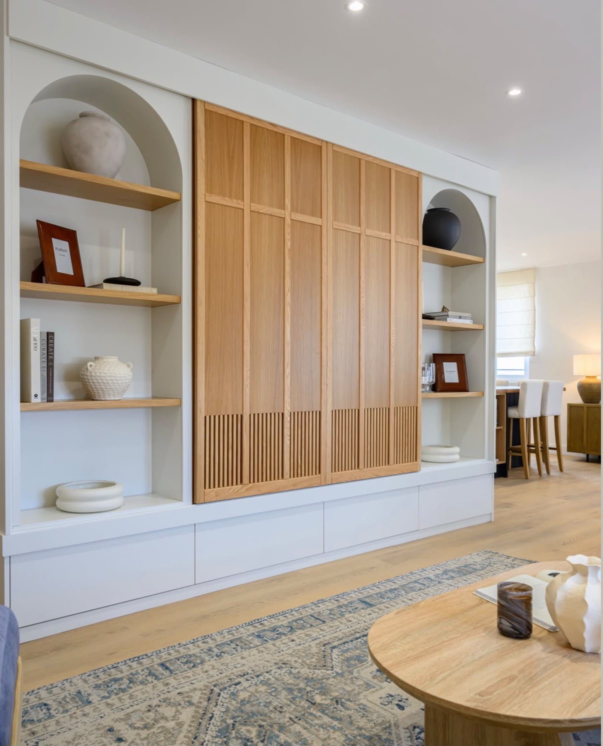 Built-in living room joinery with arched alcoves, slatted oak sliding doors and oak shelving