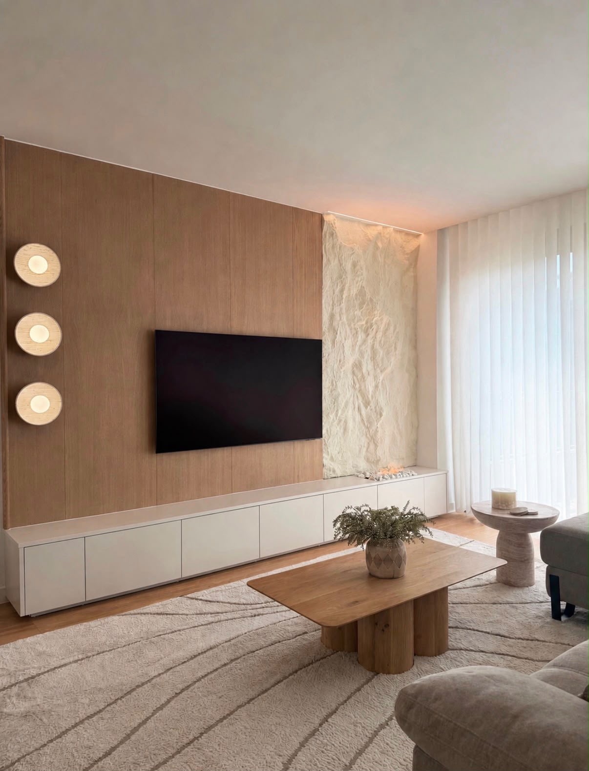 Full-height oak panelled media wall with wall-mounted TV, textured stone feature and long ivory storage unit