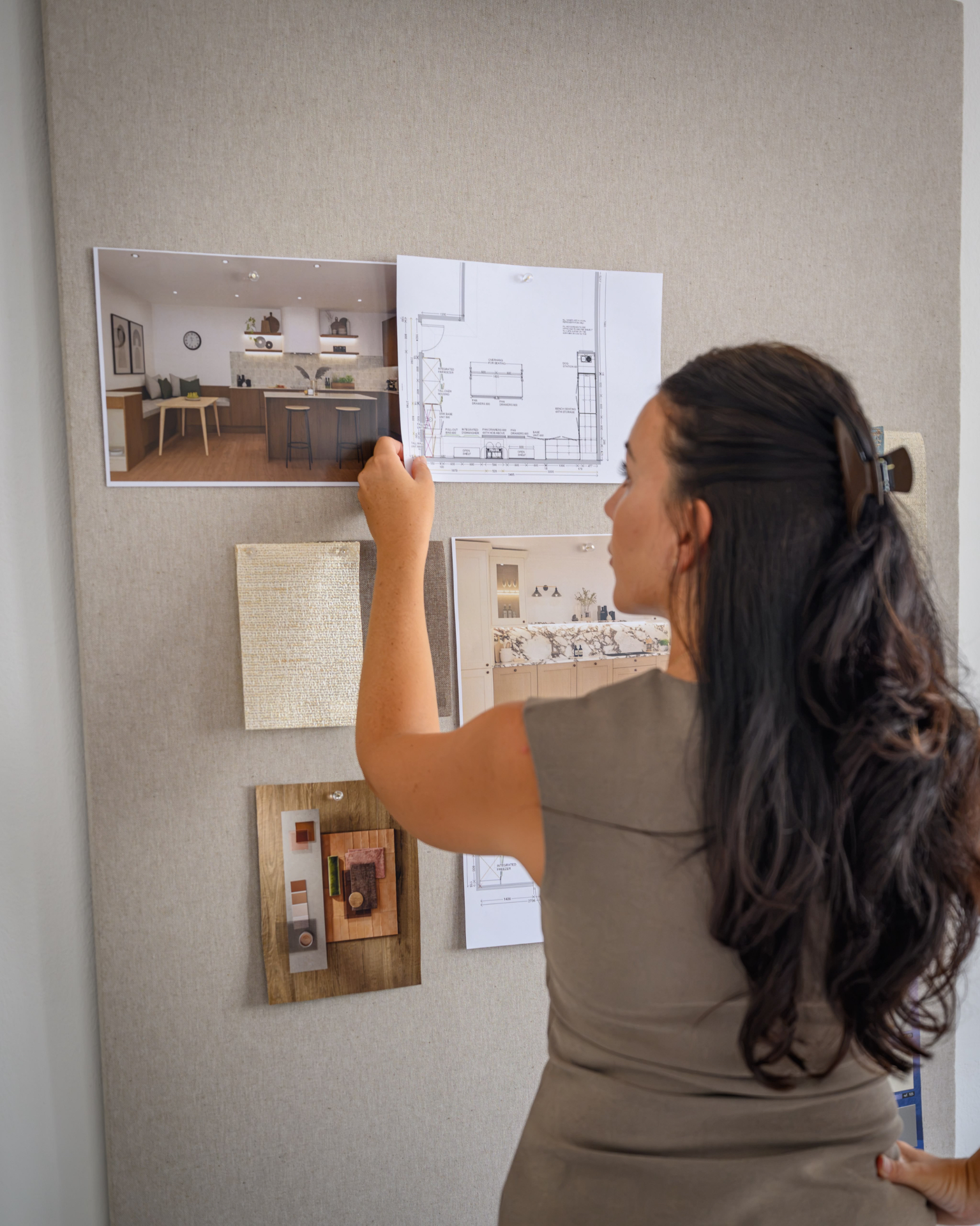 Chloe pinning design plans and material samples to a studio mood board